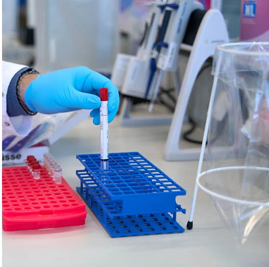 Laborant zet een buisje met testmateriaal in een rek in het laboratorium