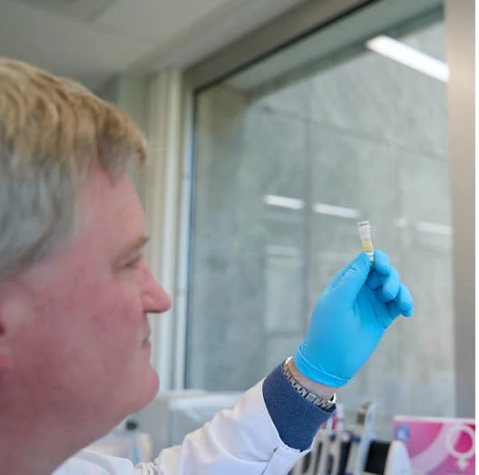 Laborant houdt een buisje met testmateriaal tegen het licht in het laboratorium