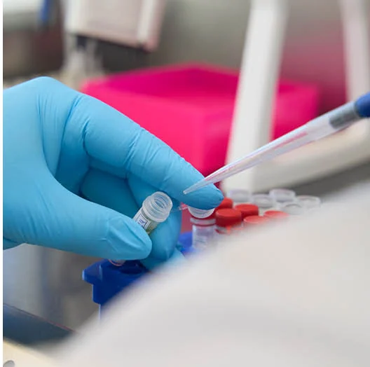 Laborant pipetteert vloeistof in een buisje om het ingestuurde monster te onderzoeken